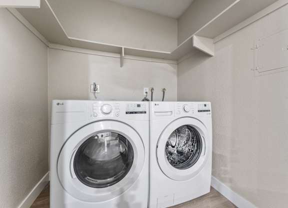 Two white front loading washing machines in a laundry room at Tamarack Sands Apartment Homes, Carlsbad, California
