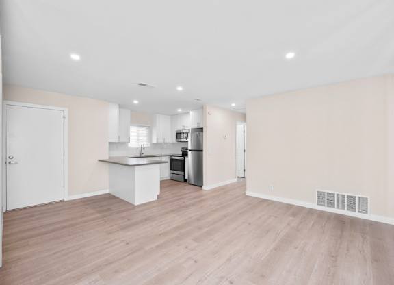 A kitchen with a white countertop and wooden flooring.