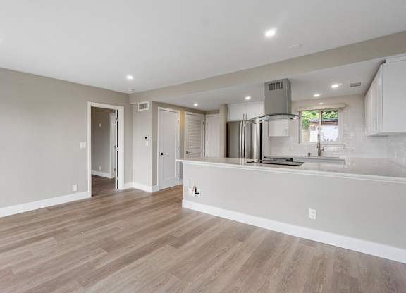 A kitchen with a refrigerator, sink, and cabinets.