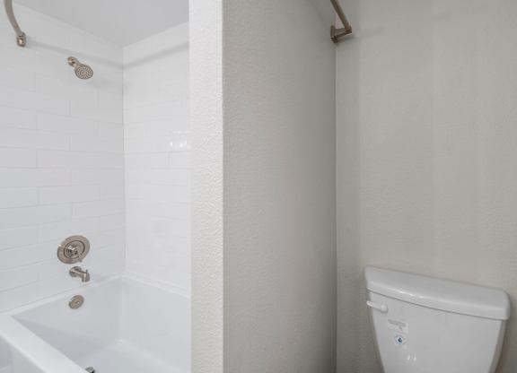 A white toilet in a bathroom with a white tub and shower.