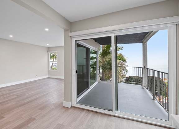 A room with a sliding glass door leading to a balcony.