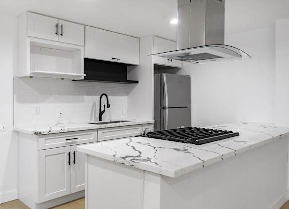 A kitchen with white cabinets and a marble countertop. at Torrance Gateway Apartments, California