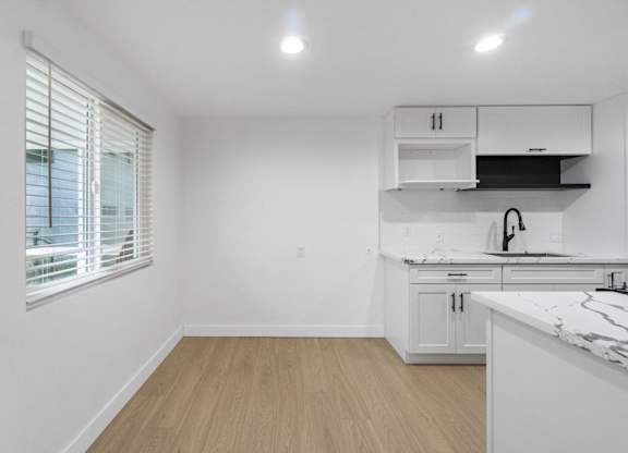 A kitchen with white cabinets and a marble countertop. at Torrance Gateway Apartments, Torrance