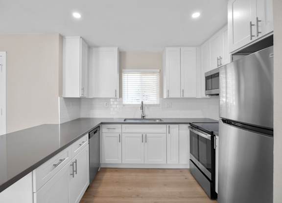 A modern kitchen with white cabinets and a stainless steel refrigerator.