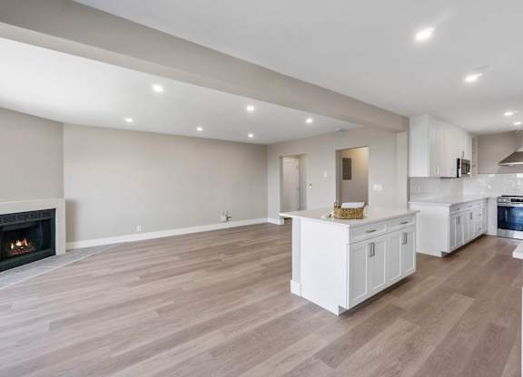 A modern kitchen with a fireplace and wooden floors.