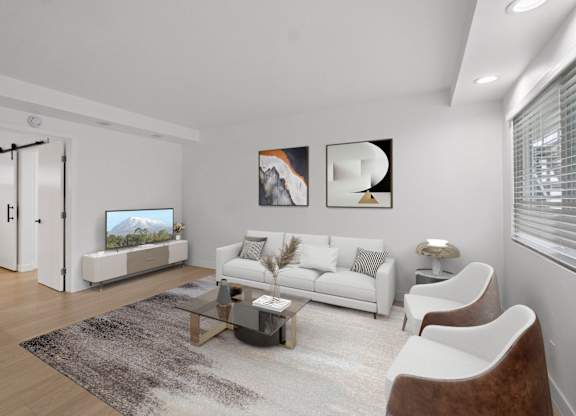 A modern living room with a white sofa, a glass coffee table, and a TV.