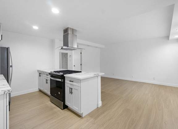 A kitchen with white cabinets and a black stove top oven. at Torrance Gateway Apartments, California