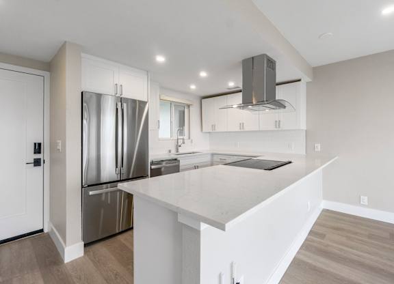 A modern kitchen with a white island and stainless steel appliances.