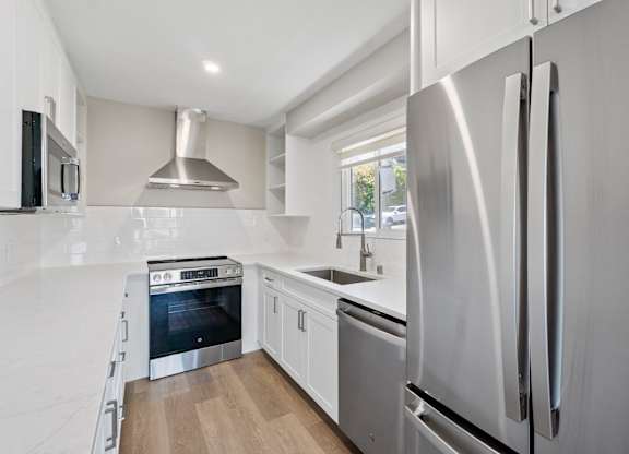 A modern kitchen with a stainless steel refrigerator and a wooden floor.