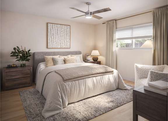 A bedroom with a large bed, a ceiling fan, and a nightstand with a plant on it.