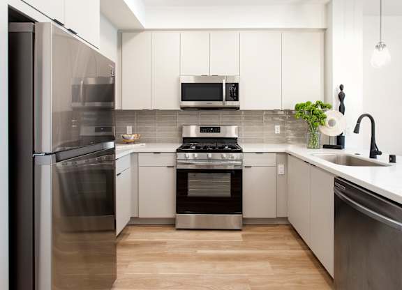 A modern kitchen with stainless steel appliances and white cabinets. at The Reserve La Mirada, La Mirada