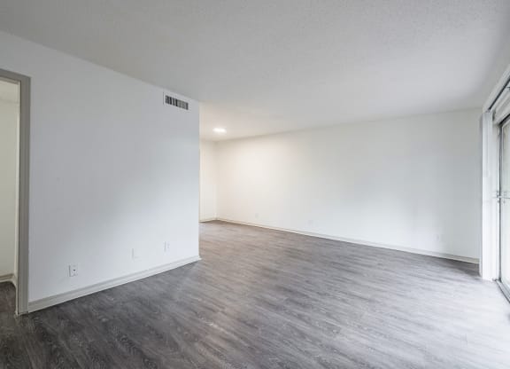 an empty living room with white walls and wood flooring
