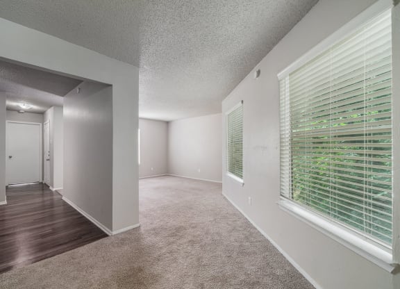 the spacious living room and dining room of an apartment with a large window  at Shadow Ridge, Arlington, 76013