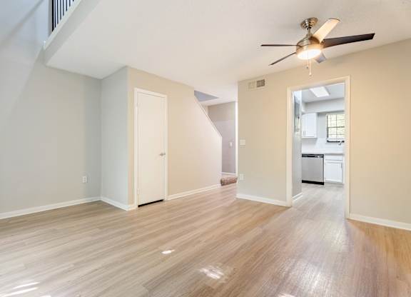 A room with a ceiling fan and light fixture, hardwood floors, and a view into a kitchen. at Rosen at North Hills, North Carolina