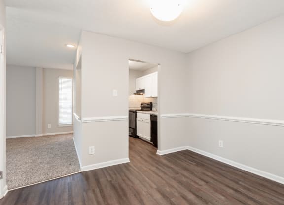 an empty living room and kitchen with white walls and wood flooring
