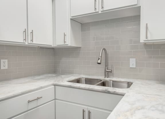 a white kitchen with a sink and white cabinets