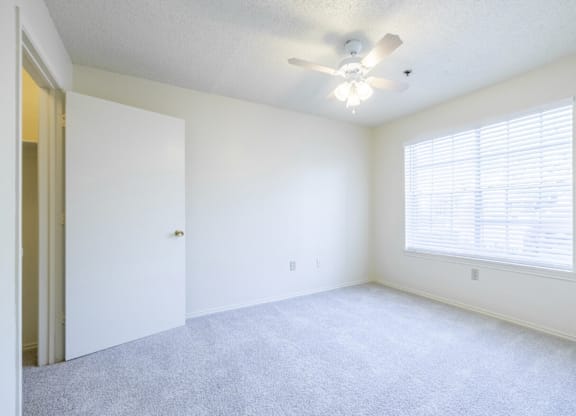 A room with a ceiling fan and a window with blinds.
