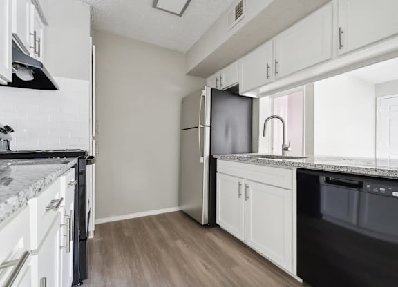 A kitchen with white cabinets and a black fridge.
