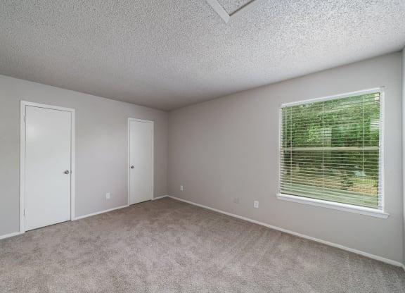 an empty bedroom with a large window and carpeted flooring  at Shadow Ridge, Arlington, Texas
