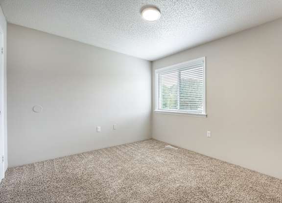 A room with a window and carpeted floor.