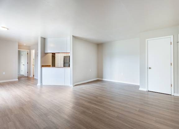 A spacious room with wooden flooring and white walls.