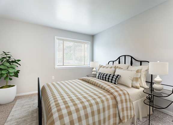 A bedroom with a bed, a potted plant, and a lamp.