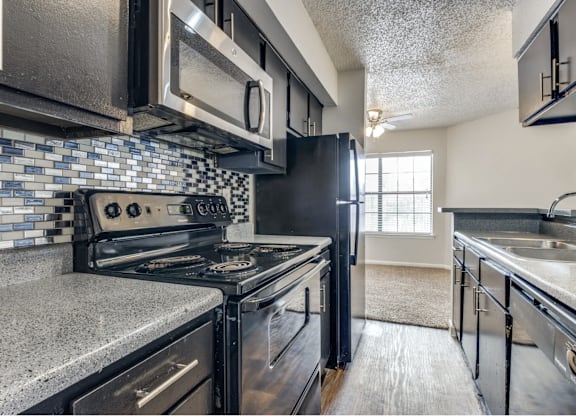 A kitchen with a black stove top oven and black cabinets.