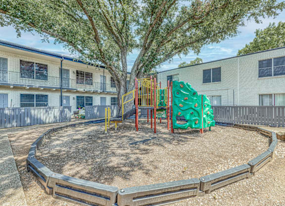 Playground with climbing structure and shade tree at Northwood Heights Apartments, Dallas, TX