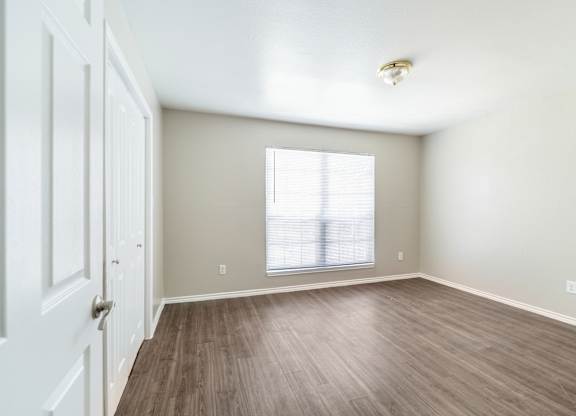 Spacious bedroom with laminate flooring and blinds at Lumina Apartments, Dallas, TX