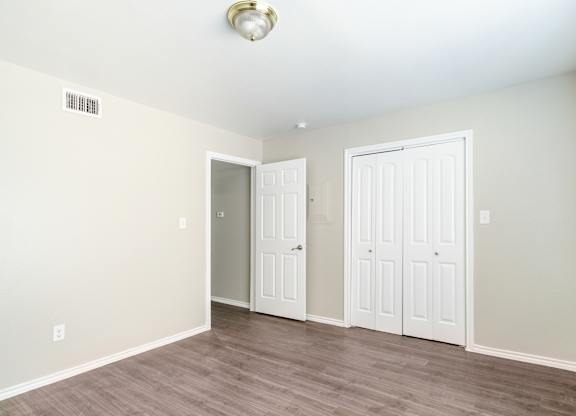 Bright bedroom with closet and wood floors at Lumina Apartments, Dallas, Texas
