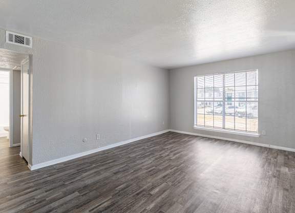 A room with wooden flooring and a window overlooking a parking lot. at Carisma, Dallas, TX, 75240