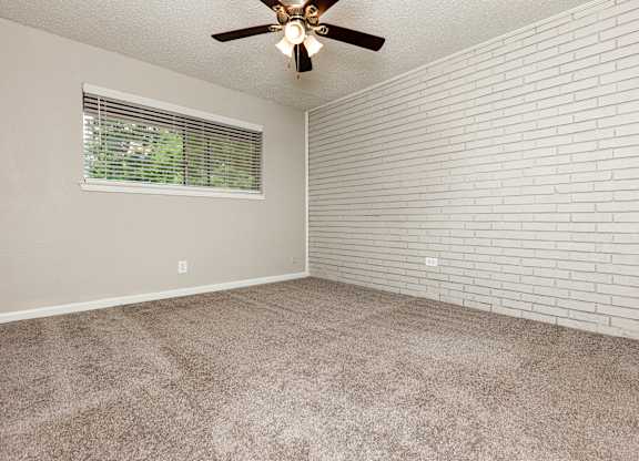 A room with a ceiling fan and a window with blinds.