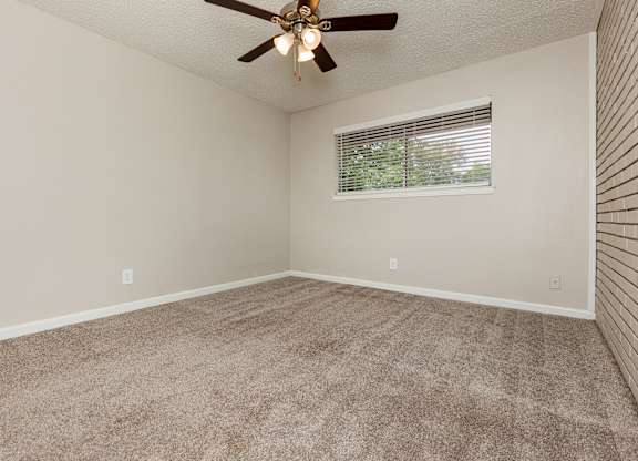 A room with a ceiling fan and a window with blinds.