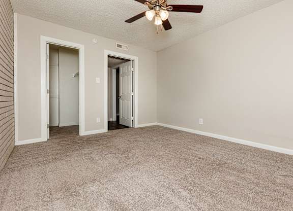 A room with a ceiling fan and carpeted floor.