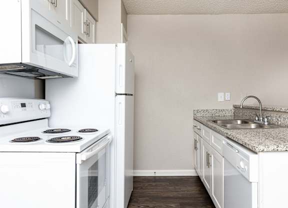 A white kitchen with a stove, oven, and sink.