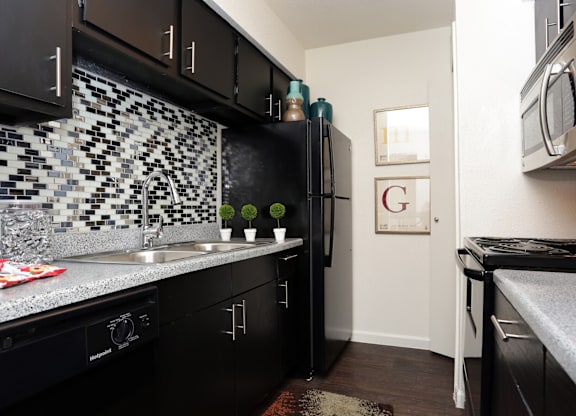 A kitchen with black cabinets and a white fridge.