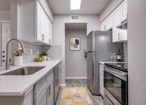 A kitchen with a sink, refrigerator, and oven.