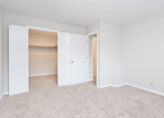 a bedroom with a closet and a carpeted floor