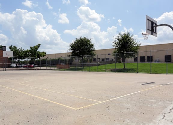 A basketball court with a basketball hoop and a fence surrounding it.