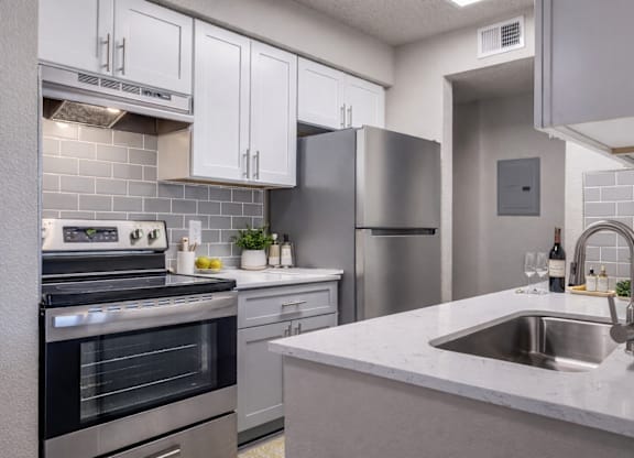 A modern kitchen with a stainless steel refrigerator, oven, and sink.