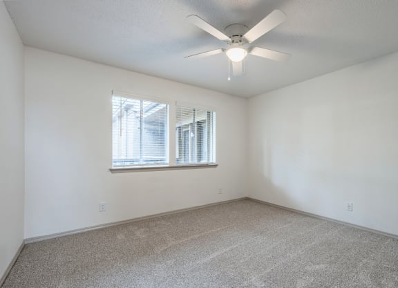 an empty room with a ceiling fan and a window