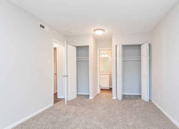 a spacious bedroom with closet doors and a carpeted floor
