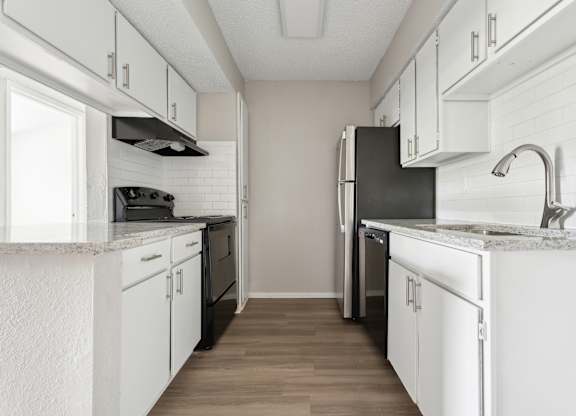A kitchen with white cabinets and a black refrigerator. at Anson at North Hills, Raleigh, North Carolina