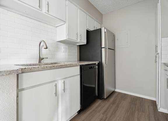 A kitchen with white cabinets and a black fridge. at Anson at North Hills, Raleigh