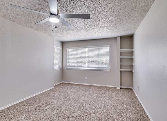 A room with a ceiling fan and a window with blinds.