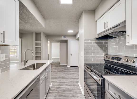 A modern kitchen with white cabinets and a tiled backsplash.