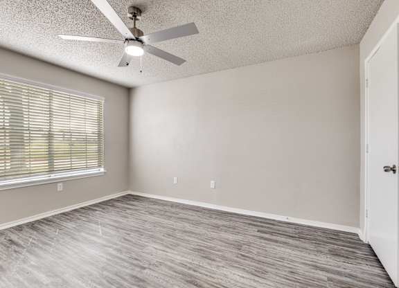 A room with a ceiling fan and a window with blinds.
