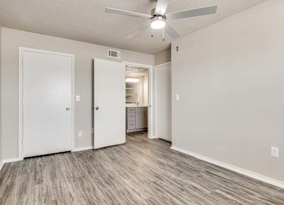 A room with a ceiling fan and light, two doors, and a cabinet with drawers.