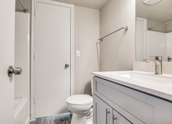 A white bathroom with a toilet, sink, and shower.