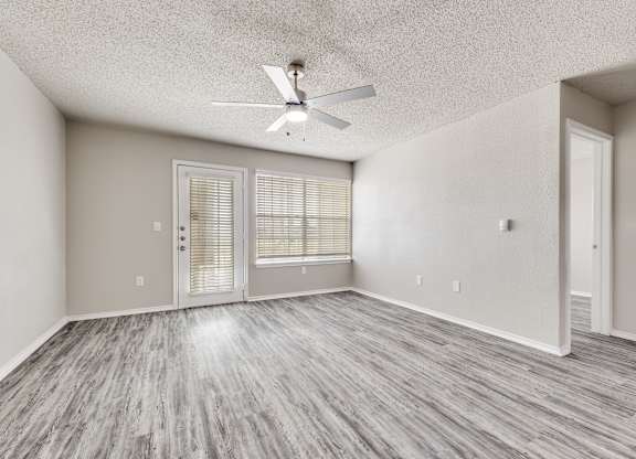 A room with a ceiling fan and sliding glass doors.